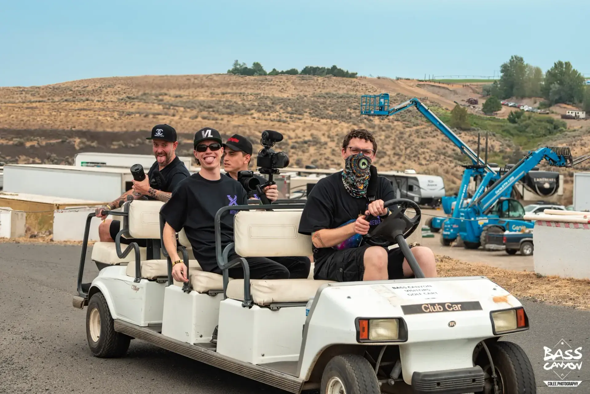 Group carrying camera equipment in a white golf cart beside a dry hillside, Bass Canyon 2022 at The Gorge Amphitheatre, George, Washington