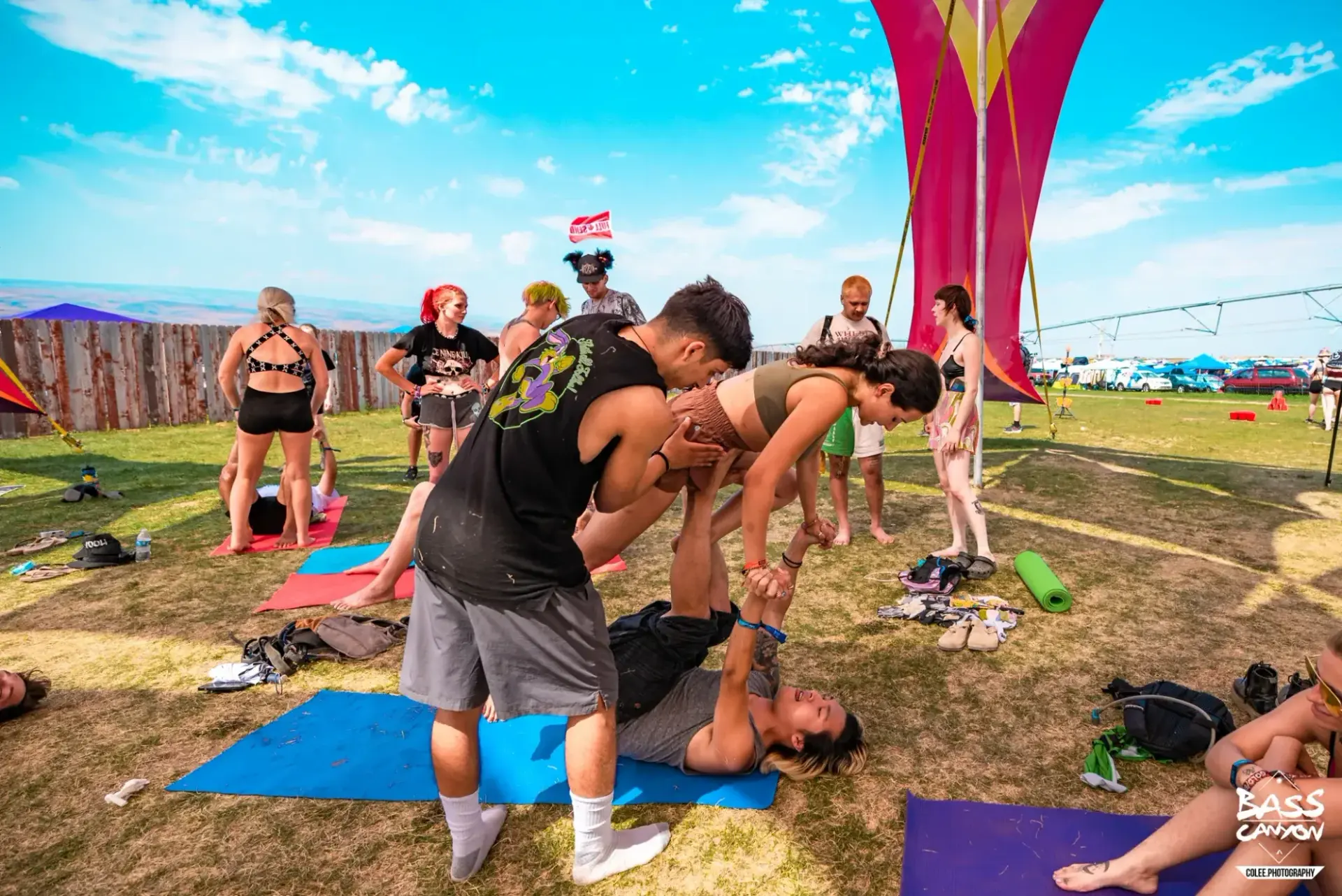 Standing helpers supporting a balancing pair on a blue mat, Bass Canyon 2022 at The Gorge Amphitheatre, George, Washington