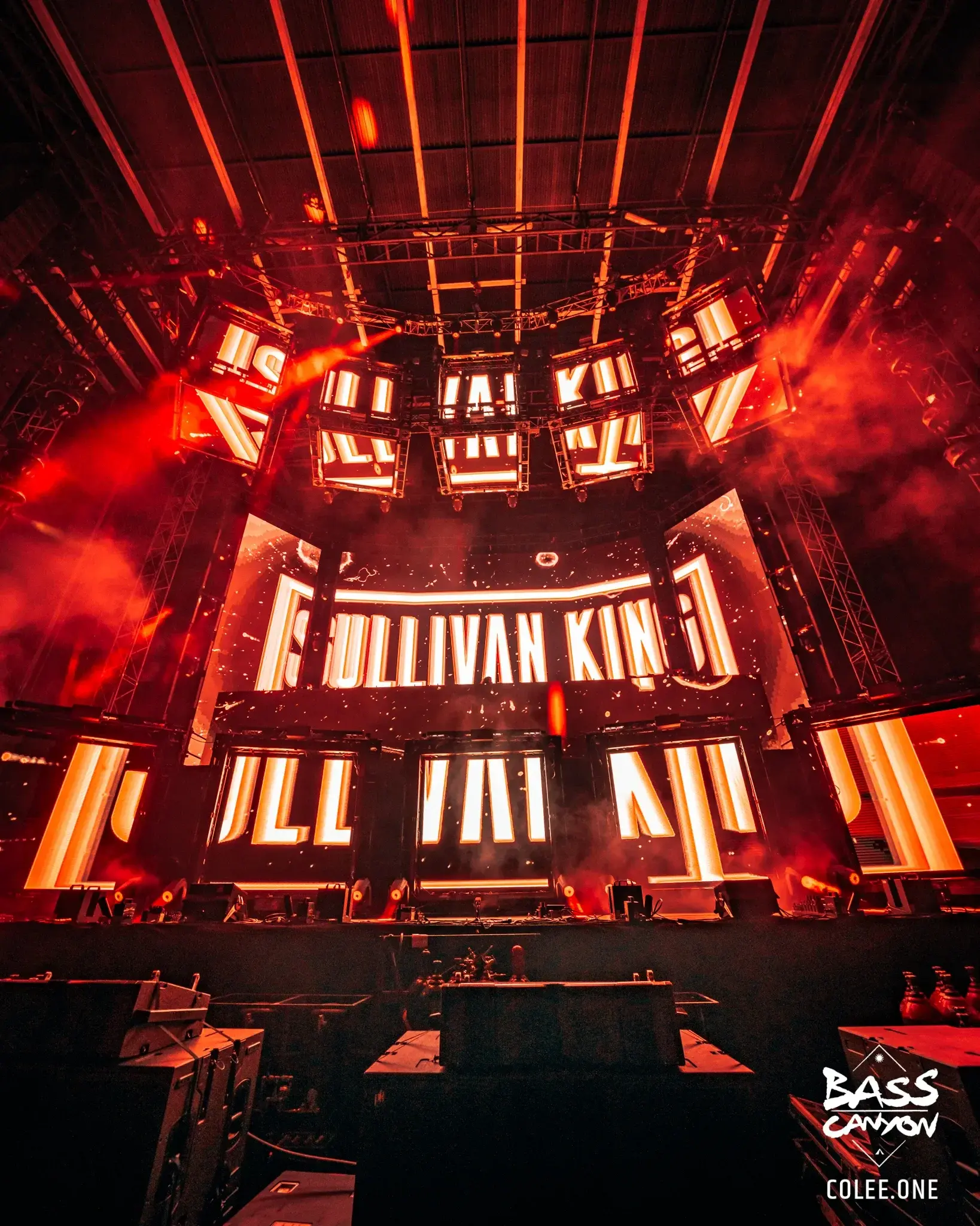Upward view of a red-lit stage with large lettering across its central screens, Bass Canyon 2023 at The Gorge Amphitheatre, George, Washington